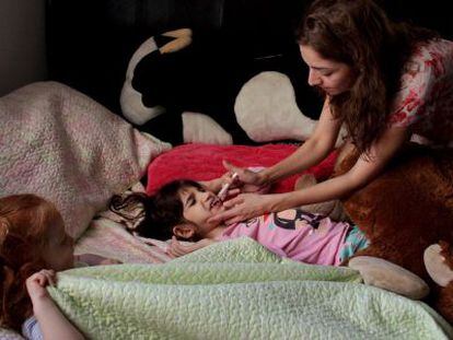A mãe de Graciela Elizalde dá o remédio a sua filha.