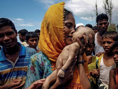 Uma mulher chora enquanto segura seu filho que morreu afogado quando um bote em que estavam virou antes de chegar a Bangladesh.