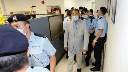 O empresário Jimmy Lai, no centro, escoltado pela polícia na redação do ‘Apple Daily’, nesta segunda-feira, em Hong Kong.