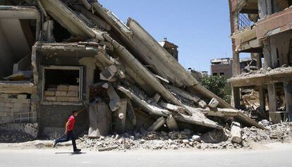 Um menino brinca em frente a um edifício destruído em Damasco.