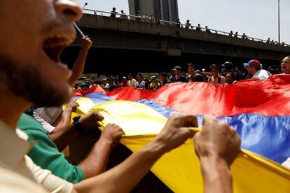 Manifestantes contrários a Maduro erguem bandeira da Venezuela.