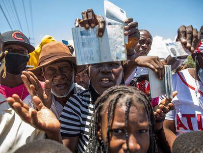 Cidadãos haitianos mostram seus passaportes para pedir asilo em frente à embaixada dos Estados Unidos em Tabarre, neste sábado.