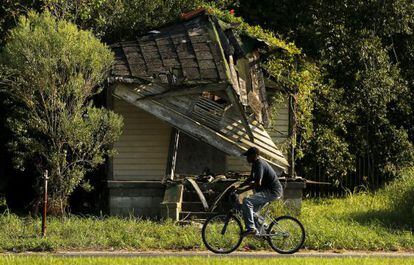 Homem passa diante de casa abandonada no Distrito 9 de Nova Orleans.
