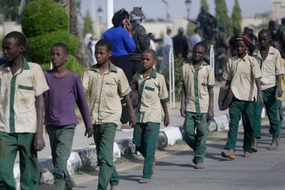 Alguns dos estudantes nigerianos que ficaram seis dias sequestrados caminham em fila em direção a um prédio do Governo, após serem libertados, nesta sexta-feira, na cidade de Katsina.