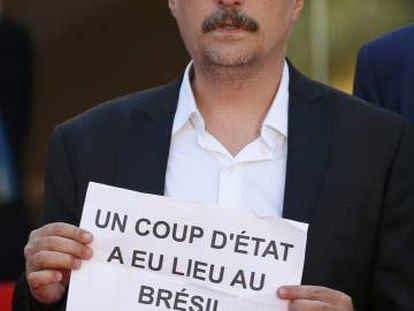 No tapete vermelho de Cannes, Kleber Mendonça Filho segura cartaz no qual denuncia que “um golpe de Estado aconteceu no Brasil”.