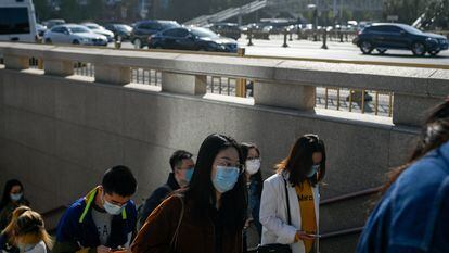 Um grupo de pessoas sai de uma passagem subterrânea em Pequim.