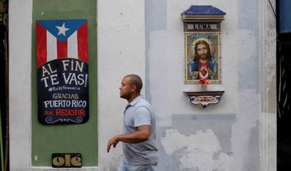 Um homem caminha junto a um cartaz que comemora a demissão do governador Ricardo Rosselló.