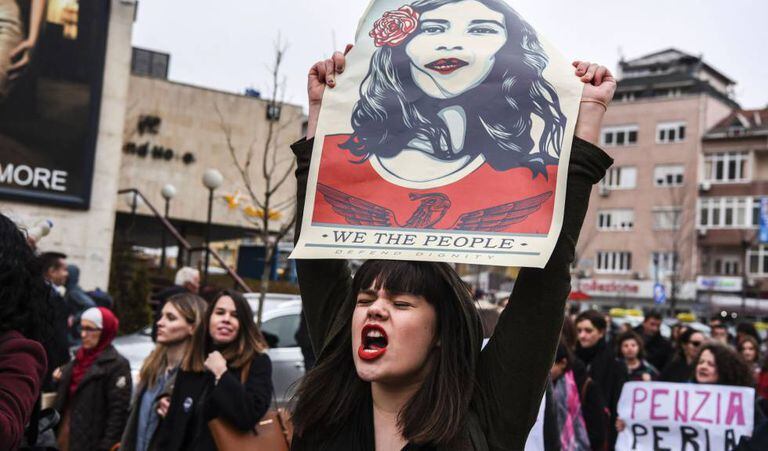Mulher com um cartaz que diz “Nós, o povo, defendemos a dignidade”, durante manifestação em Kosovo em março.
