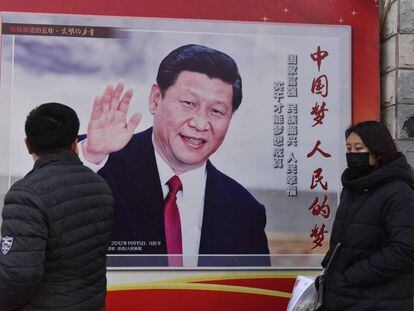 Duas pessoas passam diante de um cartaz com a foto do presidente Xi Jinping em Pequim, nesta segunda-feira.