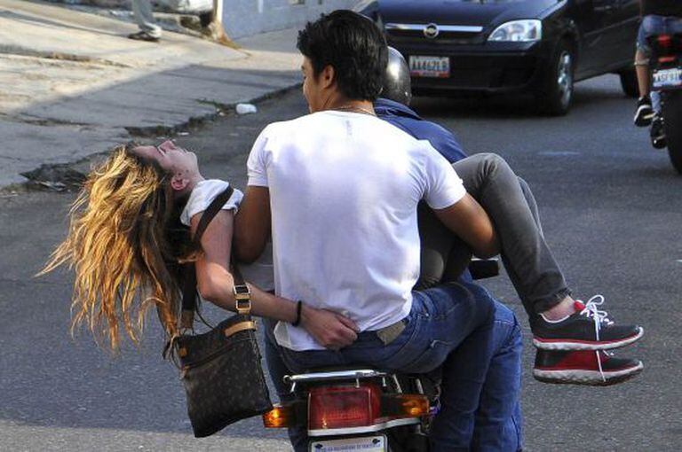 Genesis Carmona é levada em uma moto depois de ser atingida por um tiro.