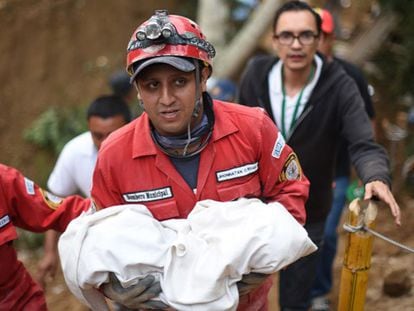 Um membro da equipe de resgate carrega o cadáver de uma criança.