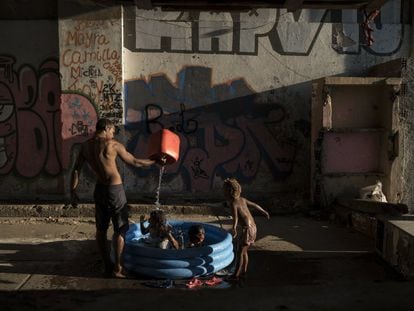 Homem banha crianças em uma favela do Rio de Janeiro.