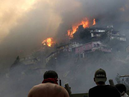 Vários homens contemplam o incêndio na serra Rocuant, de Valparaíso, na noite de terça-feira.