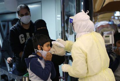 Funcionário de aeroporto na Arábia Saudita mede a temperatura de uma criança vinda da China, onde começou a circular o coronavírus.
