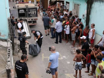 Moradores de Vitória observam a Polícia Civil retirar um corpo em uma rua no Espírito Santo, nesta sexta-feira.