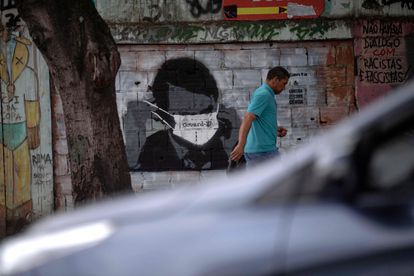 Homem caminha diante de grafite do presidente Bolsonaro, no Rio.