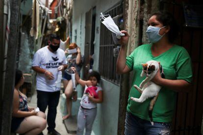 Mulkher acena com máscara cedida pela Central Única das Favelas (CUFA)em Heliópolis, São Paulo, Brazil, em 18 de junho.