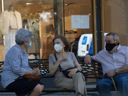 Três pessoas com máscaras conversam sentadas num banco, em Madri, na quarta-feira passada.