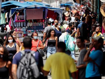 Jovem sem máscara caminha em uma movimentada rua comercial em São Paulo, no momento em que o Brasil vive uma aceleração da pandemia.