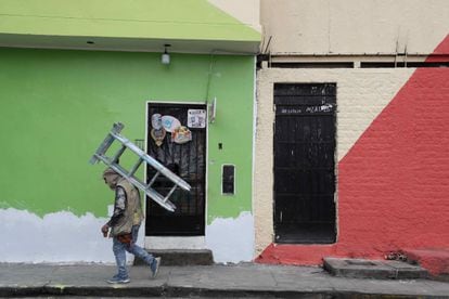 Um pintor de paredes caminha com uma escada nas costas enquanto trabalha nas fachadas das casas de San Cristóbal, em 18 de agosto passado, em Lima.