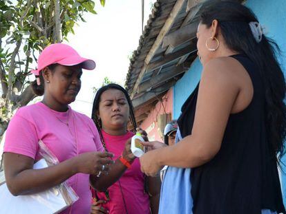 Funcionária distribui repelentes e preservativos a várias mulheres em Barranquilla, na Colômbia, na campanha contra o zika.