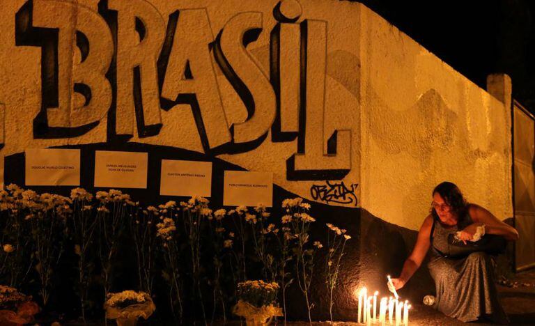 Mulher acende vela em tributo a vítimas do ataque em Suzano.