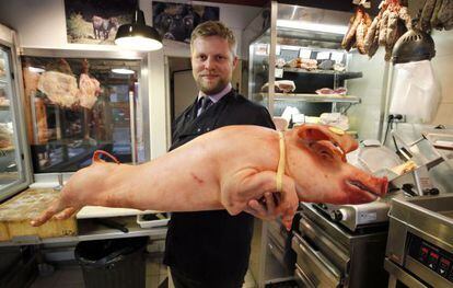 O açougueiro francês Bastien Nicolas posando com um porco.