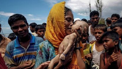 Uma mulher chora enquanto segura seu filho que morreu afogado quando um bote em que estavam virou antes de chegar a Bangladesh.
