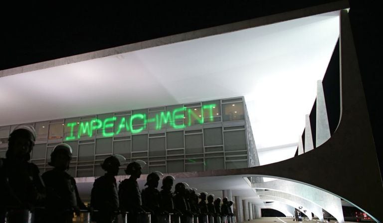 Manifestantes projetam a palavra impeachment no Palácio do Planalto.