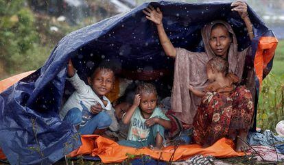 Refugiados da etnia rohingya se protegem da chuva com um plástico no campo de Cox’s Bazar, em Bangladesh