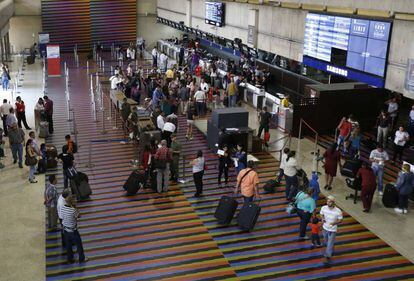 Passageiros na área de despacho de bagagens do aeroporto Simón Bolívar.