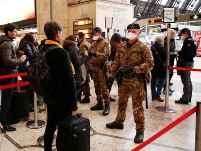 Agentes da polícia e soldados revistam passageiros em um posto de controle na estação central de Milão.