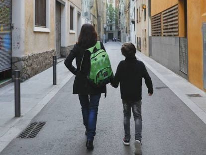 Uma mãe carrega a mochila de seu filho a caminho da escola