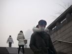 Una mujer con mascarilla camina a través de un paso inferior. Los residentes de Beijing se despertaron el día de Navidad con el cielo oscurecido por una espesa niebla tóxica.