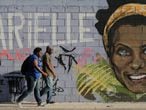 Dos personas pasan por delante de un grafiti con la cara de Marielle Franco.