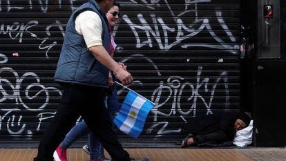 Mulher dorme na cal&ccedil;ada enquanto pessoas caminham durante a celebra&ccedil;&atilde;o do bicenten&aacute;rio da independ&ecirc;ncia argentina, em Buenos Aires. 