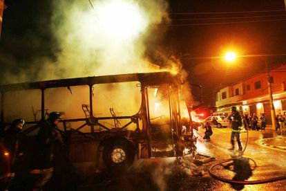 Bombeiros apagam chamas de &ocirc;nibus incendiado por integrantes do PCC na Vila Madalena, zona oeste de S&atilde;o Paulo, em maio de 2006. V&aacute;rios &ocirc;nibus foram incendiados naquela semana. 