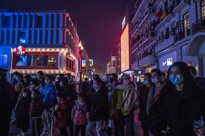Grupo de pessoas usando máscara ouve músicos de rua em uma área comercial do centro de Wuhan. 