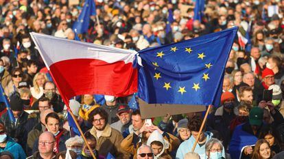 Vários manifestantes erguem bandeiras da Polôniaeda UE, em uma marcha no domingo emCracóvia.