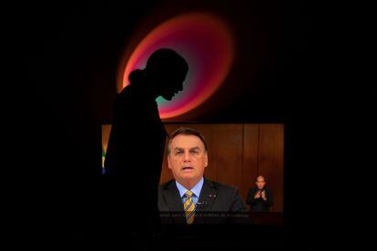 Mulher grita "Fora, Bolsonaro" enquanto presidente brasileiro discursa na TV.