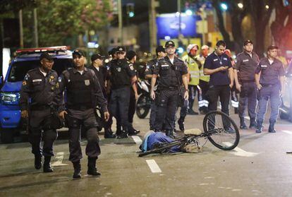 Policiais ao lado do corpo de um homem morto, perto do estádio do Maracanã no dia da cerimônia de abertura.