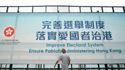 Um homem passa diante de um cartaz que promove a reforma eleitoral, nesta terça-feira, em Hong Kong.