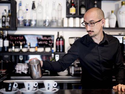 Um garçom prepara três cafés em um bar de Madri.