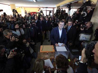 O premi&ecirc; Mariano Rajoy vota neste domingo, cercado por jornalistas.