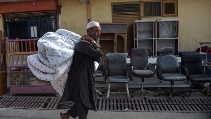 Um afegão vai ao mercado de segunda mão no bairro de Khari Khana, em Cabul, para vender um colchão e sua roupa de cama, no domingo.
