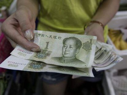 Vendedora mostra notas de yuan em Pequim.
