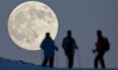 Três praticantes de esqui de montanha contemplam a lua cheia em Weissfluhjoch, em Arosa (Suíça), um dia antes do solstício de inverno.