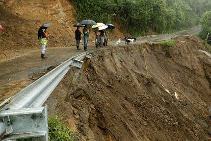 Algumas pessoas olham uma estrada parcialmente destroçada pelas chuvas em Costa Rica.