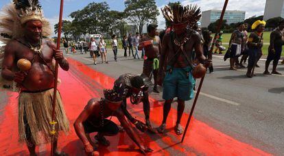 Índios pintam o chão para simbolizar o genocídio indígena no Brasil.