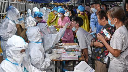 Agentes sanitários fazem exames maciços de covid-19 em Cantão (China), no domingo.